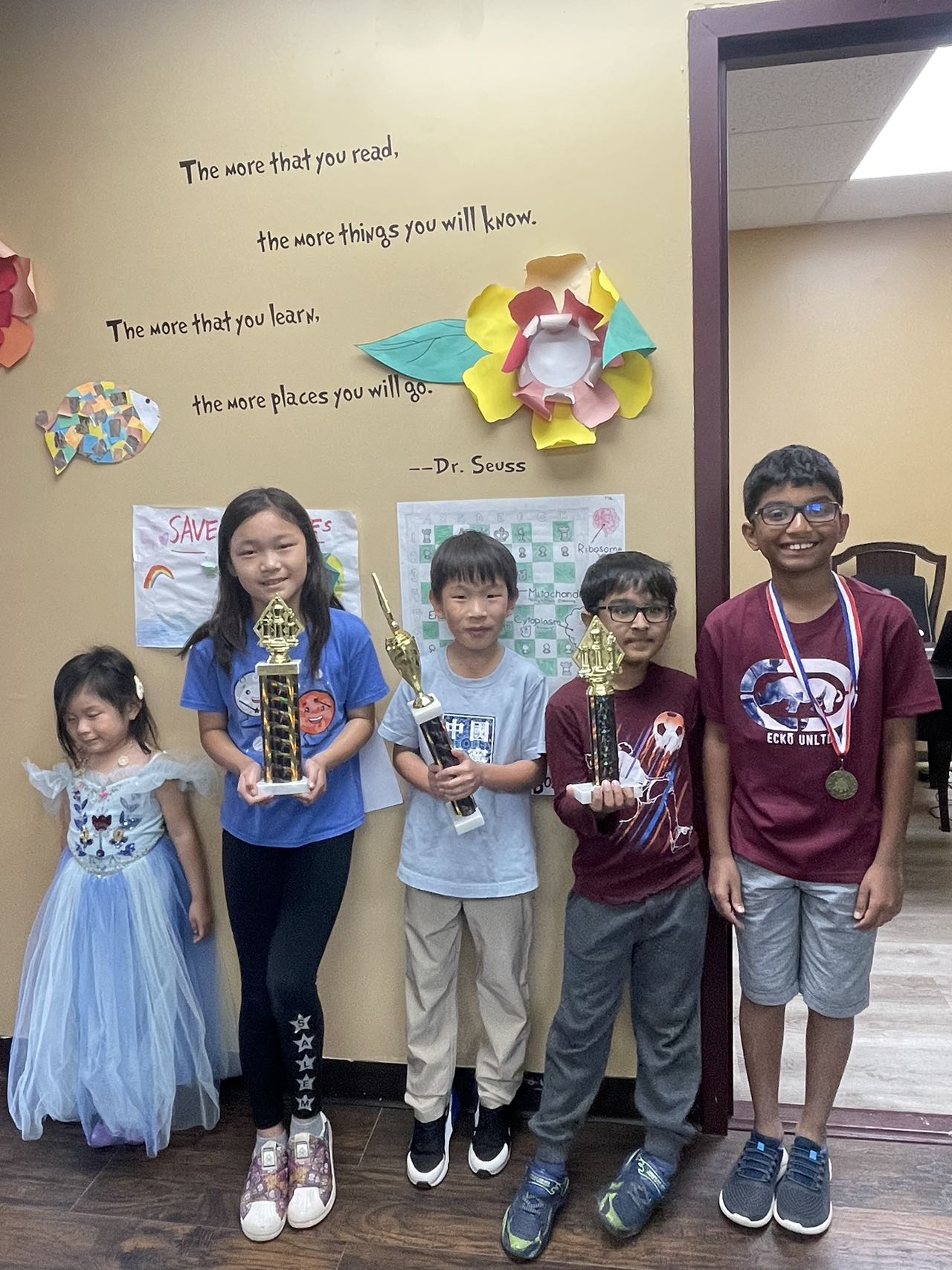 Four students proudly holding their competition trophies